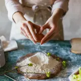 Mains préparant un œuf pour des ingrédients de pâtisserie. Farine, lait et œufs sont prêts pour la création d'une recette.
