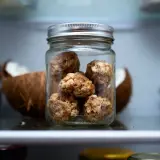 Bocal de conservation de rochers coco, une collation saine et gourmande, à côté d'une noix de coco ouverte.