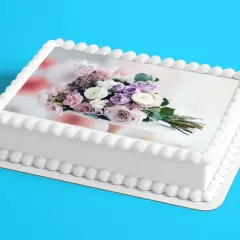 Gâteau blanc décoré d'un bouquet de fleurs roses et violettes sur une feuille azyme. Parfait pour une recette festive.