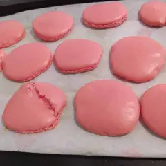 Des macarons roses sur une plaque de cuisson. Certains sont craquelés, un mystère pour comprendre pourquoi mes macarons craquent.