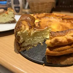 Un délicieux gâteau healthy, un cheesecake doré et crémeux, avec une part déjà servie sur une assiette blanche.