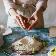 Mains préparant un œuf pour des ingrédients de pâtisserie. Farine, lait et œufs sont prêts pour la création d'une recette.