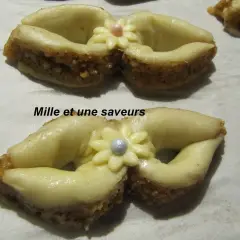 Délicieux noeud en pâte à sucre, orné d'une fleur et d'une perle, sur un lit de biscuits aux amandes.
