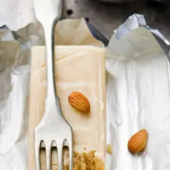 Bloc de pâte d'amande pour recouvrir un gâteau, avec une fourchette et des amandes.