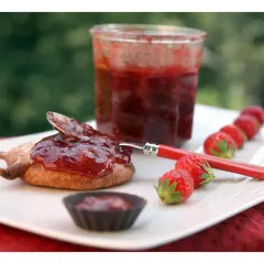 Confiture de framboise pectine sur un biscuit, avec des fraises fraîches alignées.