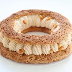 Un Paris-Brest rond, garni d'une crème onctueuse et parsemé de morceaux de praliné cacahuète croquant.