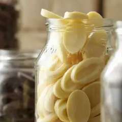 Des éclats de chocolat blanc dans un bocal, prêts pour la conservation. Le chocolat maison est un délice.