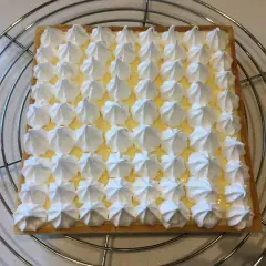 Tarte citron meringuée rectangulaire, garnie de crème citron et de petites meringues blanches disposées en grille. Un délice signé Pierre Hermé.