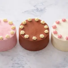 Trois petits gâteaux, une recette bento cake : rose, chocolat et vanille, décorés de crème.