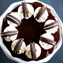 Gâteau au chocolat glacé, décoré de crème fouettée et de biscuits Oreo. Un délice pour les amateurs de layer cake Oreo.