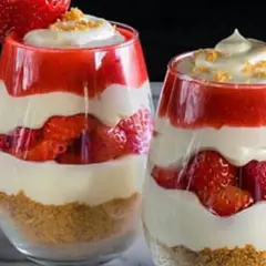 Deux verrines de gâteau fraise crème pâtissière, superposant biscuits émiettés, fraises fraîches, crème pâtissière onctueuse et coulis de fraises.