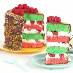 Gâteau coloré aux couches de pistache et framboise, garni de fruits rouges frais.