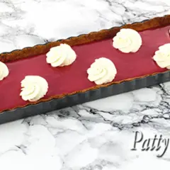 Tarte rectangulaire au curd framboise, garnie de touches de crème fouettée. Un délice fruité et gourmand.