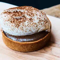 Tartelette gourmande avec une généreuse crème pour gâteau, saupoudrée de cacao. Un délice visuel.