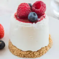 Délicieux dessert sans cuisson, un petit gâteau crémeux garni de fruits rouges frais et d'un coulis.