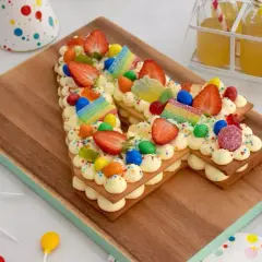 Un délicieux number cake sans crème, décoré de fraises, bonbons et vermicelles colorés, parfait pour une fête d'anniversaire.