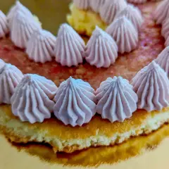Gâteau rond décoré de rosaces de ganache framboise sur un lit de fruits rouges.