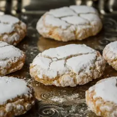 Biscuits craquelés saupoudrés de sucre glace, parfaits pour accompagner votre café. Une idée pour comment faire de la poudre d'amande maison.