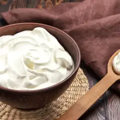 Crème diplomate onctueuse dans un bol, prête pour une recette gourmande. Une cuillère en bois en présente une portion.