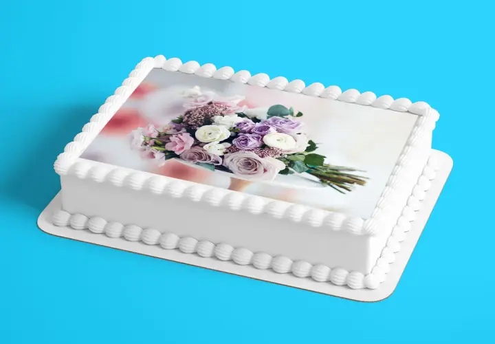Gâteau blanc décoré d'un bouquet de fleurs roses et violettes sur une feuille azyme. Parfait pour une recette festive.