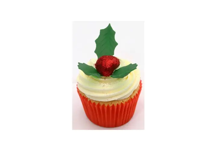 Un cupcake festif orné d'une baie rouge pailletée et d'une feuille de houx verte.
