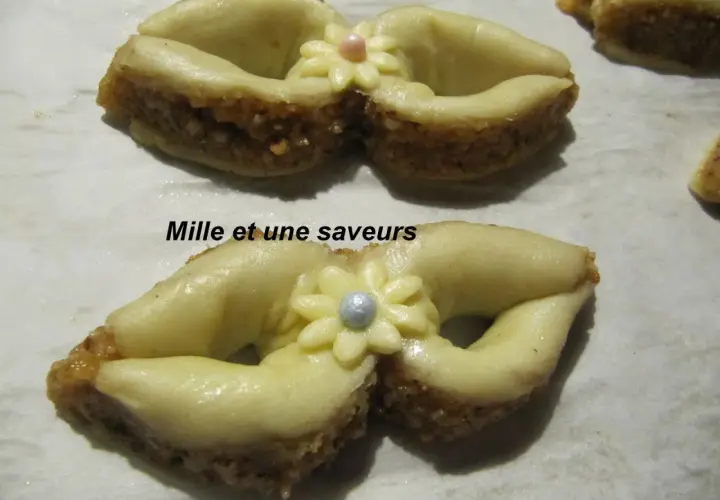 Délicieux noeud en pâte à sucre, orné d'une fleur et d'une perle, sur un lit de biscuits aux amandes.