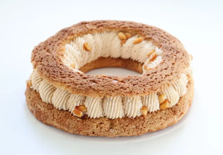 Un Paris-Brest rond, garni d'une crème onctueuse et parsemé de morceaux de praliné cacahuète croquant.