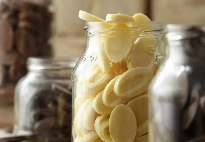 Des éclats de chocolat blanc dans un bocal, prêts pour la conservation. Le chocolat maison est un délice.