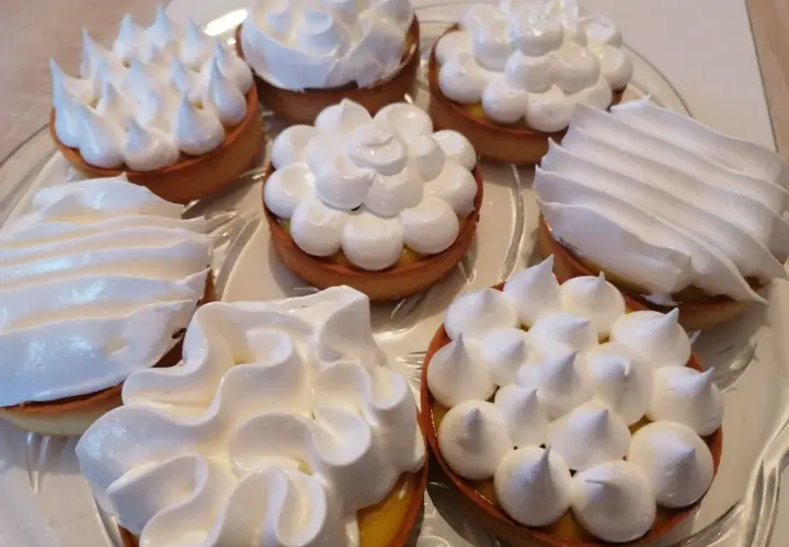 Plateau de tartelettes garnies de crème citronnée et surmontées de meringue italienne, une œuvre de conservation gourmande.