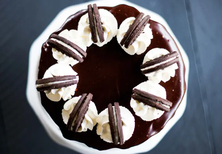 Gâteau au chocolat glacé, décoré de crème fouettée et de biscuits Oreo. Un délice pour les amateurs de layer cake Oreo.