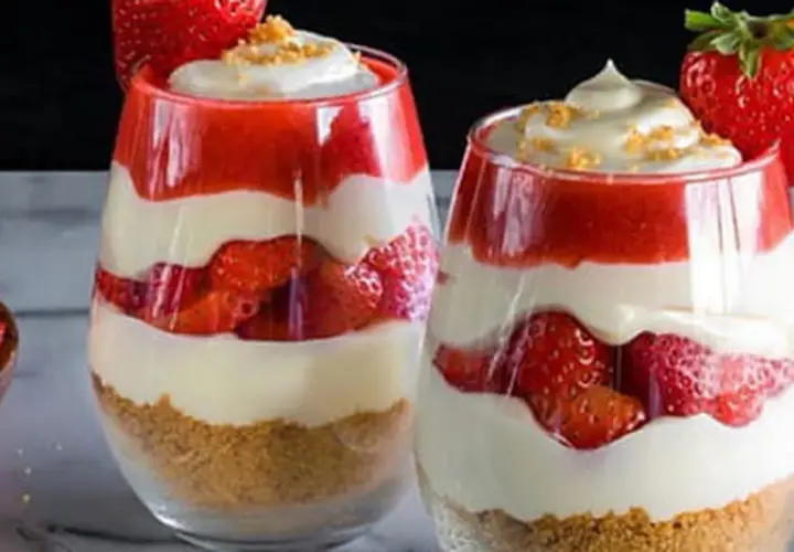 Deux verrines de gâteau fraise crème pâtissière, superposant biscuits émiettés, fraises fraîches, crème pâtissière onctueuse et coulis de fraises.