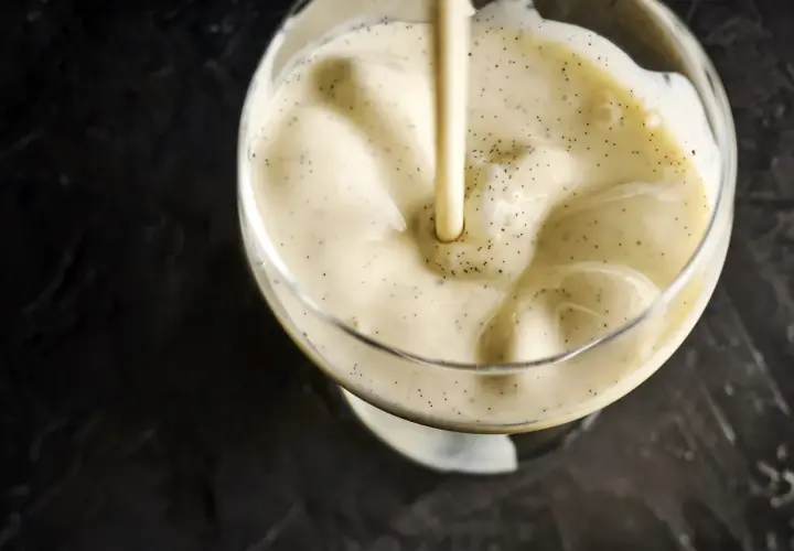 Crème vanillée versée dans un verre, évoquant la différence entre crème anglaise et pâtissière.