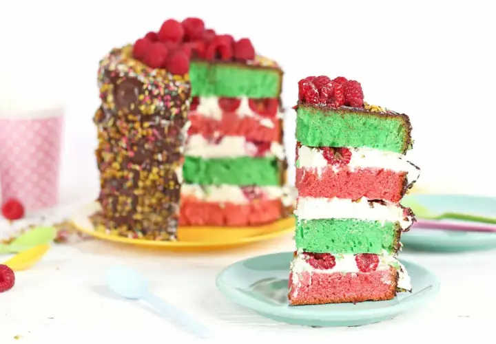Gâteau coloré aux couches de pistache et framboise, garni de fruits rouges frais.