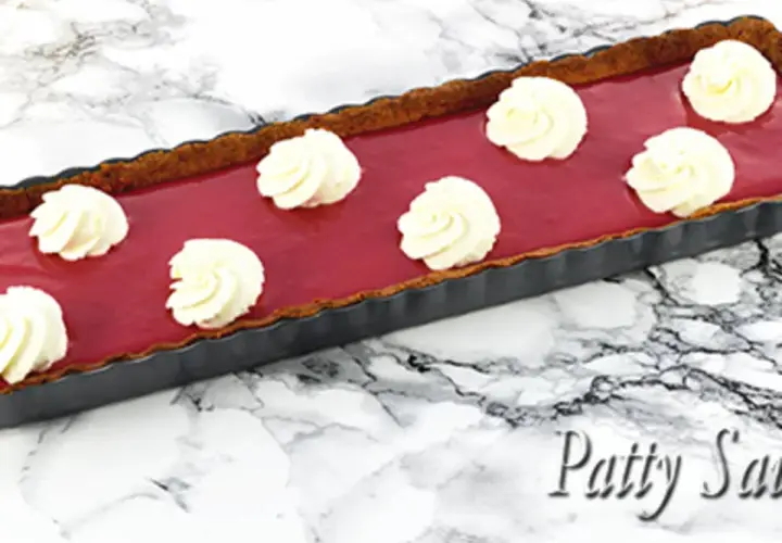 Tarte rectangulaire au curd framboise, garnie de touches de crème fouettée. Un délice fruité et gourmand.