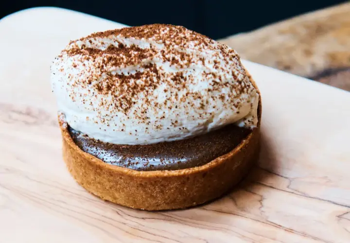 Tartelette gourmande avec une généreuse crème pour gâteau, saupoudrée de cacao. Un délice visuel.