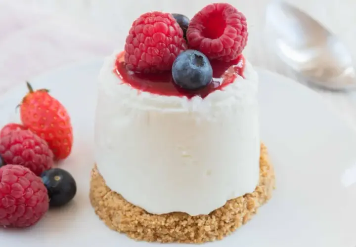 Délicieux dessert sans cuisson, un petit gâteau crémeux garni de fruits rouges frais et d'un coulis.