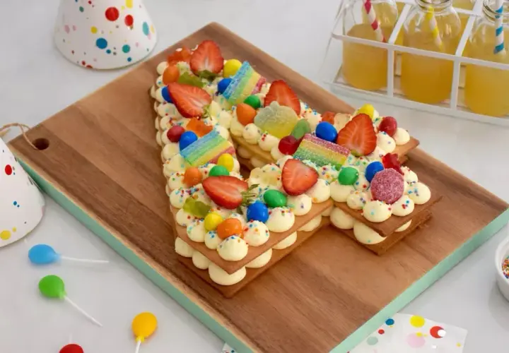 Un délicieux number cake sans crème, décoré de fraises, bonbons et vermicelles colorés, parfait pour une fête d'anniversaire.