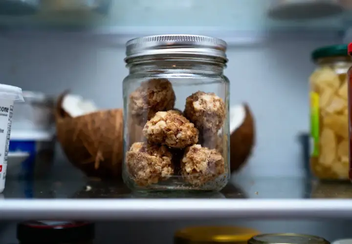 Bocal de conservation de rochers coco, une collation saine et gourmande, à côté d'une noix de coco ouverte.