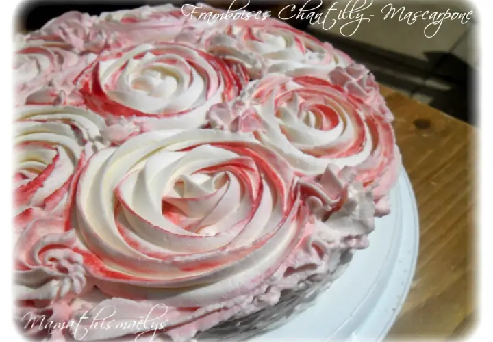 Gâteau orné de roses en chantilly mascarpone, avec des touches de framboise pour une déco gourmande.