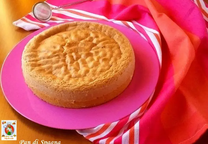 Un gâteau "Pan di Spagna" sur une assiette rose, prêt pour la conservation génoise. Un tamis est à côté.