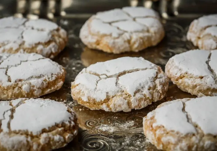Biscuits craquelés saupoudrés de sucre glace, parfaits pour accompagner votre café. Une idée pour comment faire de la poudre d'amande maison.