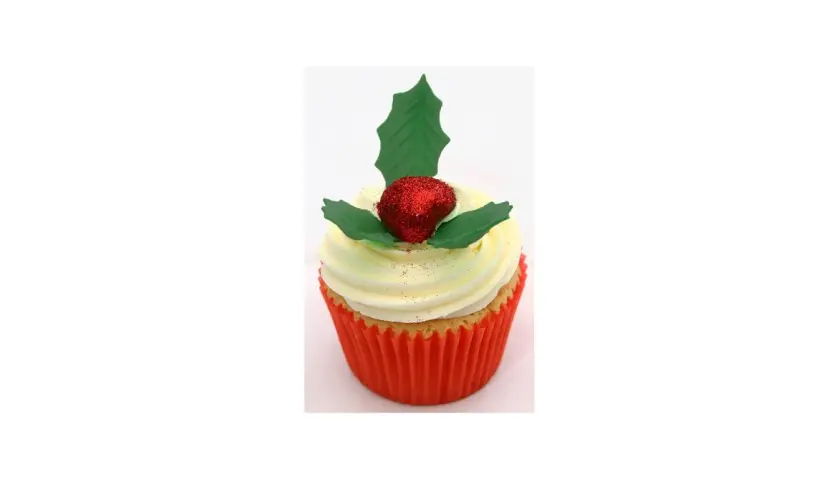 Un cupcake festif orné d'une baie rouge pailletée et d'une feuille de houx verte.