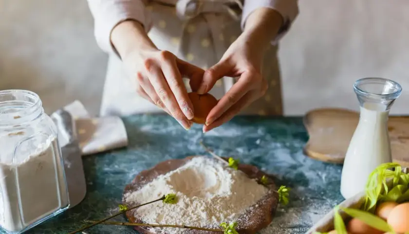 Mains préparant un œuf pour des ingrédients de pâtisserie. Farine, lait et œufs sont prêts pour la création d'une recette.