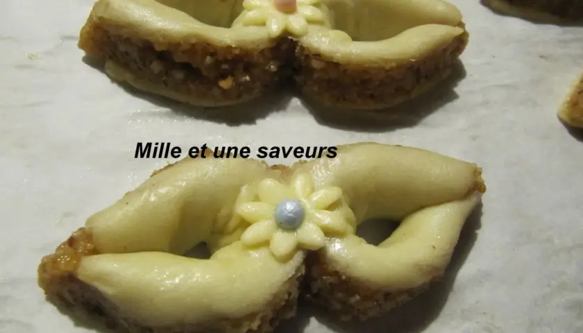 Délicieux noeud en pâte à sucre, orné d'une fleur et d'une perle, sur un lit de biscuits aux amandes.