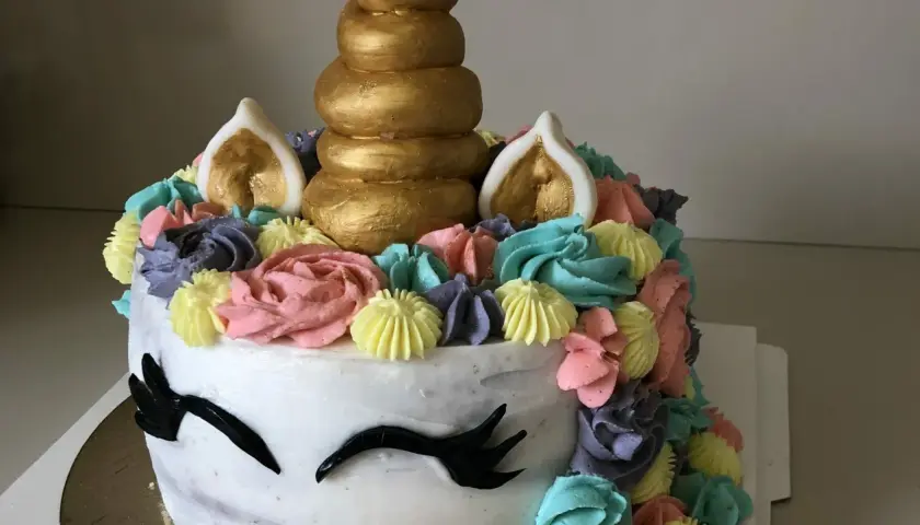 Un gâteau licorne facile sans pâte à sucre, décoré de crème colorée et d'une corne dorée. Parfait pour une fête magique !
