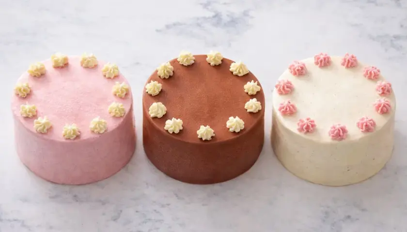 Trois petits gâteaux, une recette bento cake : rose, chocolat et vanille, décorés de crème.