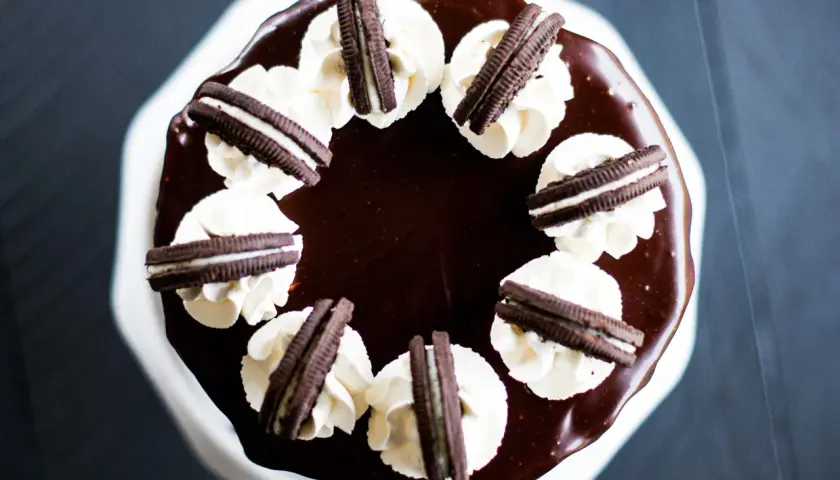 Gâteau au chocolat glacé, décoré de crème fouettée et de biscuits Oreo. Un délice pour les amateurs de layer cake Oreo.