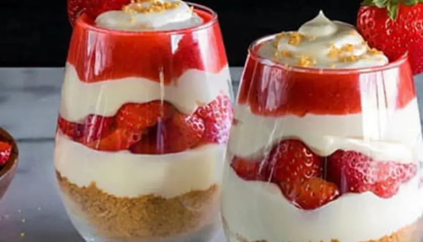 Deux verrines de gâteau fraise crème pâtissière, superposant biscuits émiettés, fraises fraîches, crème pâtissière onctueuse et coulis de fraises.