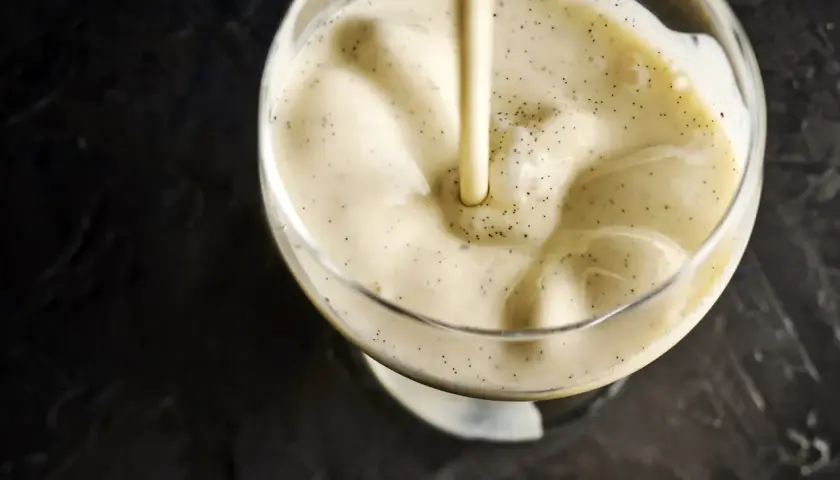 Crème vanillée versée dans un verre, évoquant la différence entre crème anglaise et pâtissière.