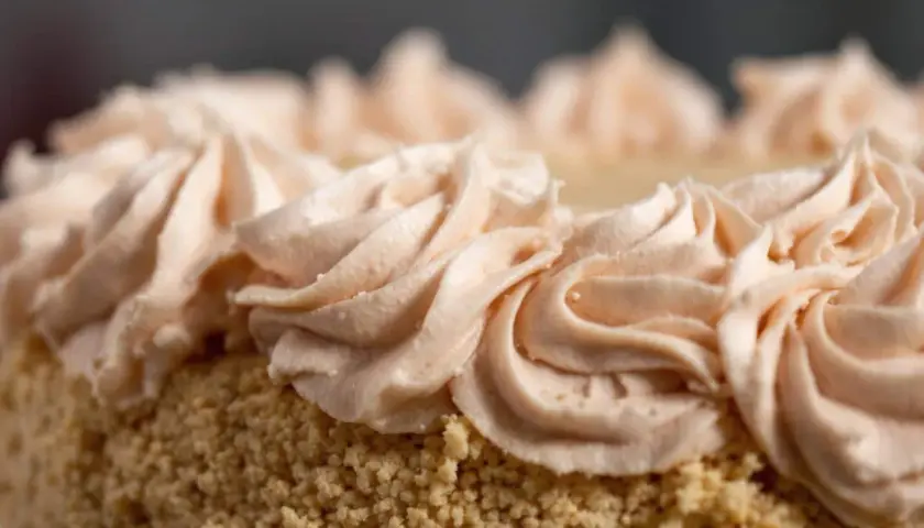 Gâteau recouvert de miettes et décoré de volutes de crème rose pâle. Une décoration gateau facile et élégante.